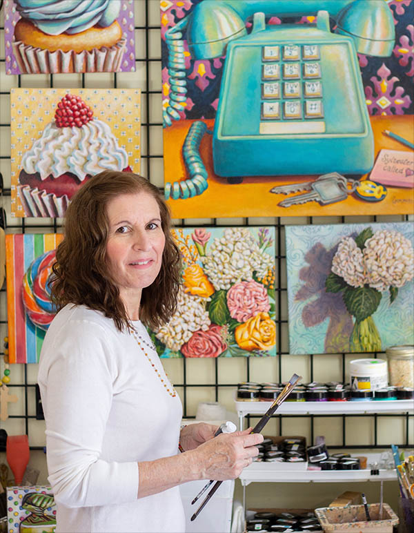 Carmen Gonzalez is standing near her paintings